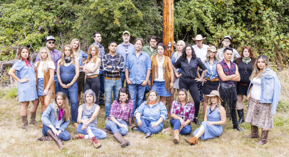 the M+P team in 2019; a group of people stands and sits in front of a forest