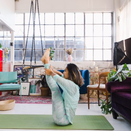 A yoga instructor performs a difficult position in a bright loft space