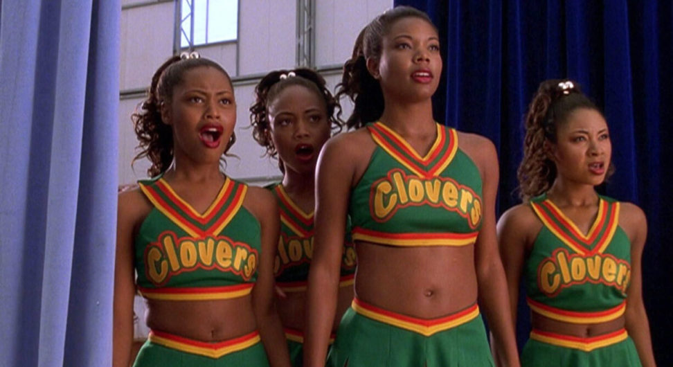 four women in cheerleader uniforms look shocked