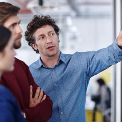 Coworkers listen intently to their peer who is avidly explaining their idea to the team